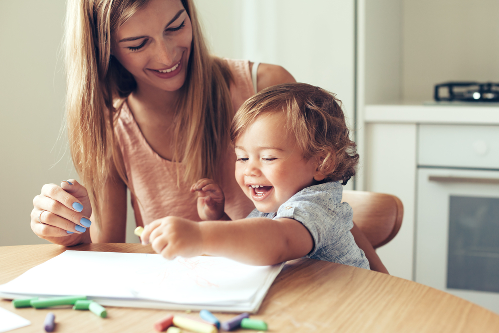 Child and mother coloring on paper and laughing